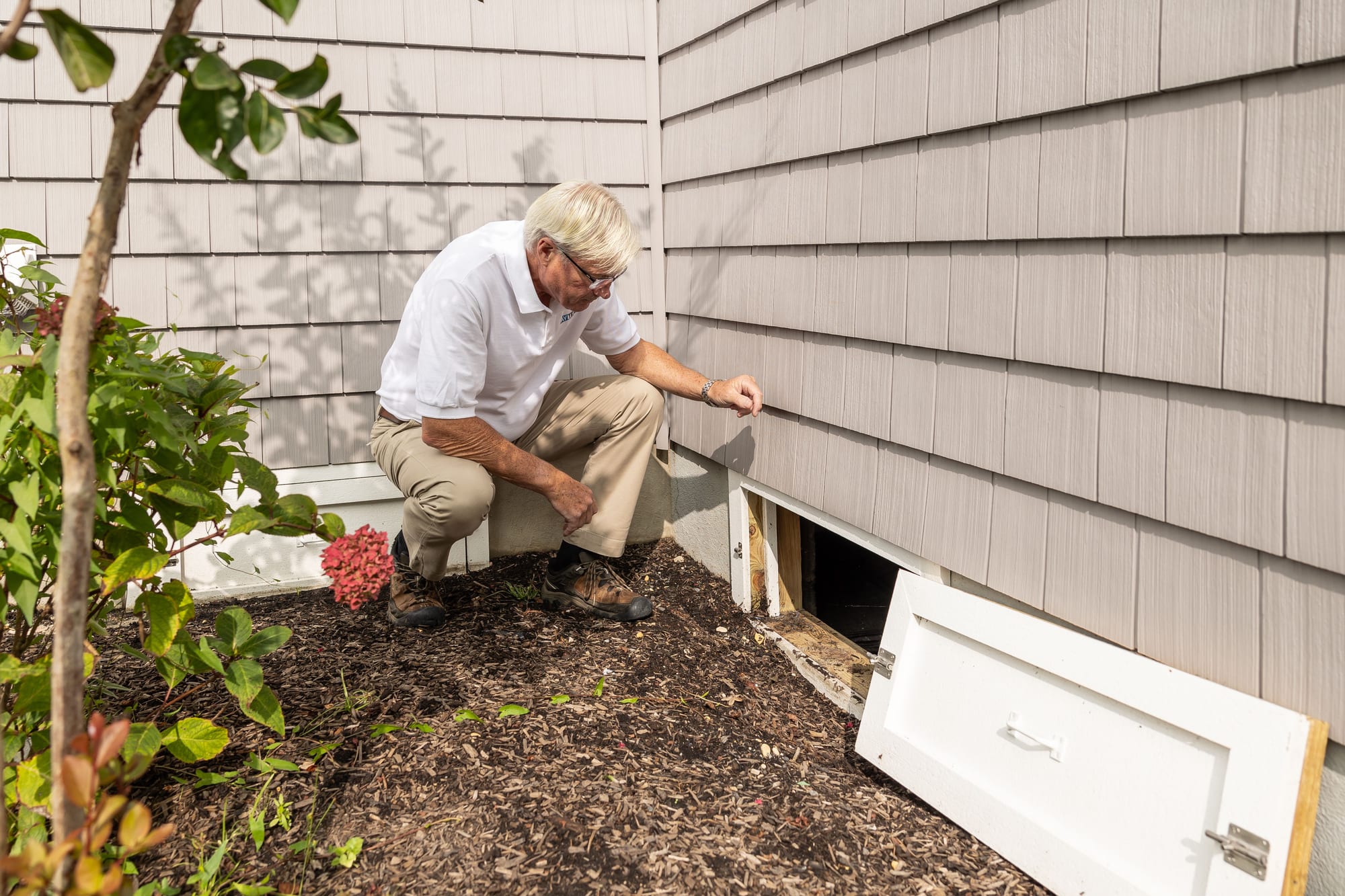 A building inspector examining a subfloor crawl space during a pre-purchase inspection