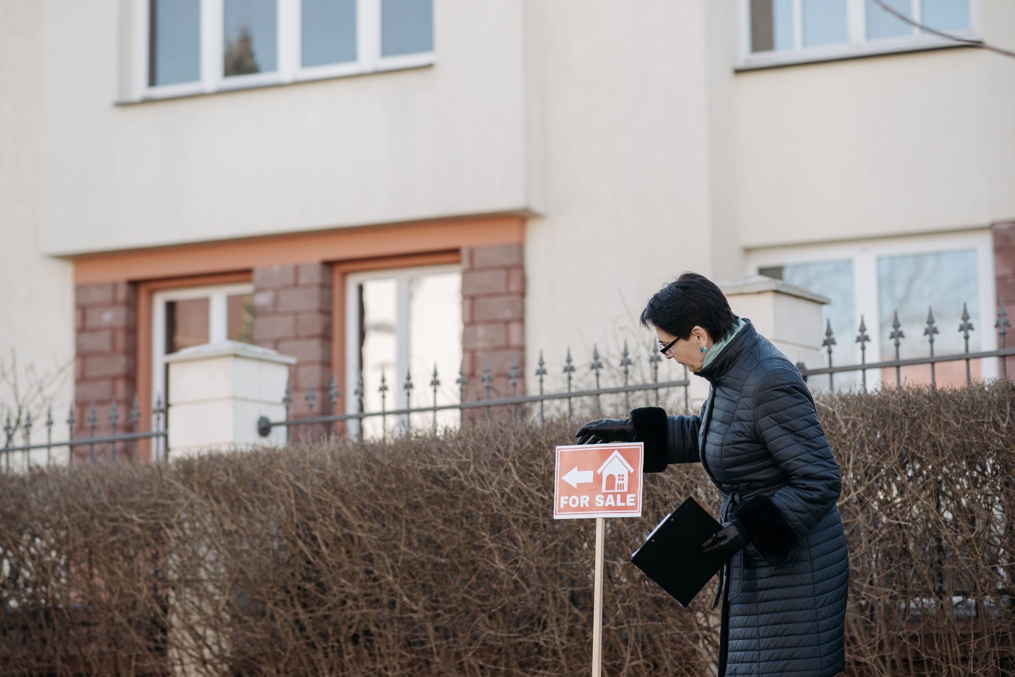 A real estate agent placing a For Sale sign in front of a house ahead of an auction campaign